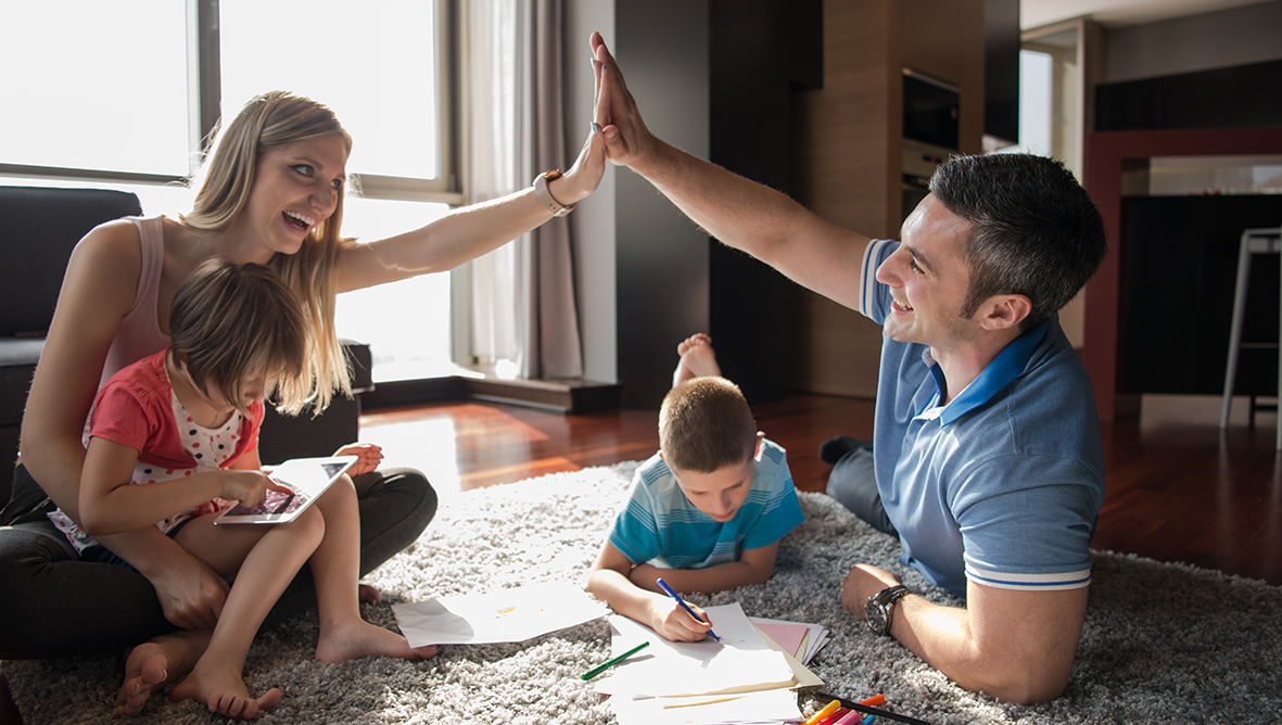 Happy Young Family Playing Together at home on the floor using a tablet and a children's drawing set